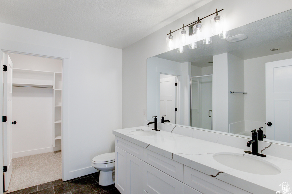 Bathroom with oversized vanity, toilet, double sink, and tile floors