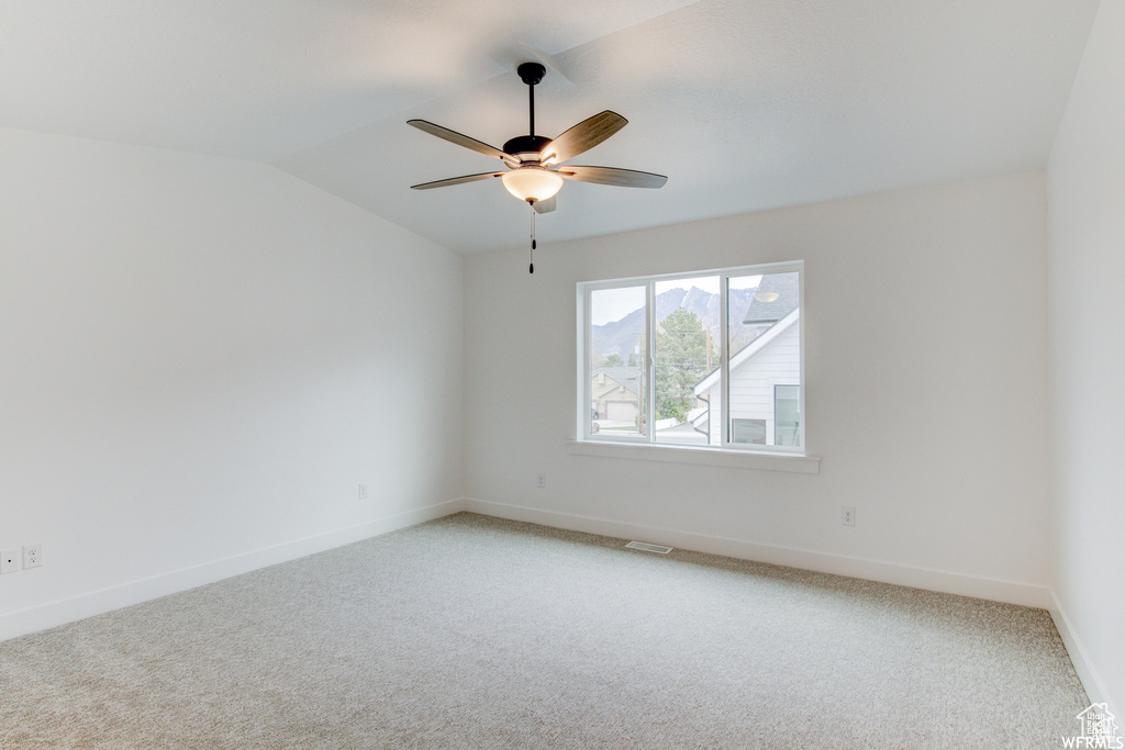 Spare room with vaulted ceiling, light colored carpet, and ceiling fan
