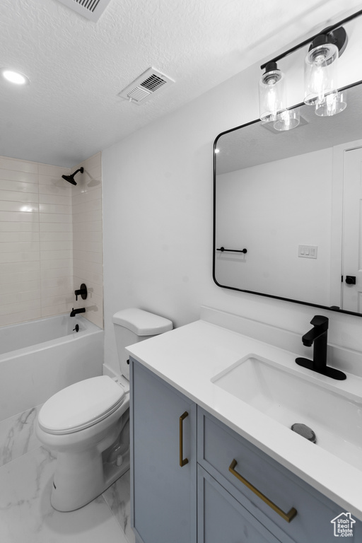 Full bathroom featuring toilet, vanity with extensive cabinet space, a textured ceiling, and tiled shower / bath