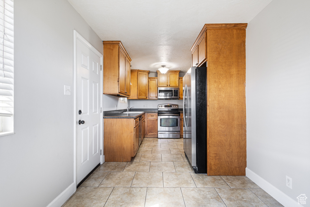 Kitchen featuring light tile flooring, appliances with stainless steel finishes, and sink