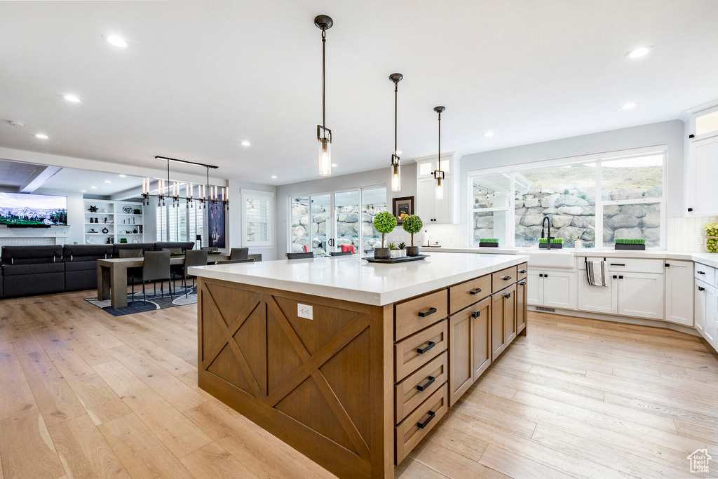 Kitchen featuring white cabinets, a center island, light hardwood / wood-style floors, and decorative light fixtures