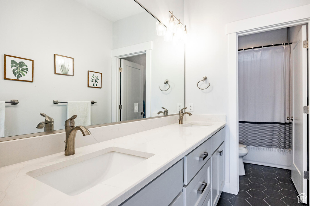 Bathroom featuring tile floors, double sink vanity, and toilet