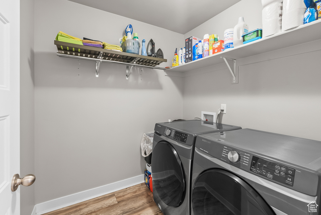 Washroom with hookup for a washing machine, hardwood / wood-style floors, and washer and clothes dryer