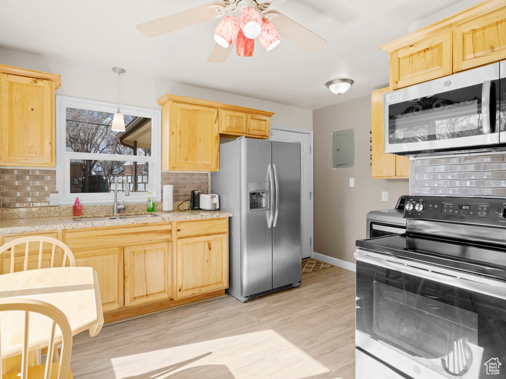 Kitchen featuring ceiling fan, light wood-type flooring, stainless steel appliances, and backsplash