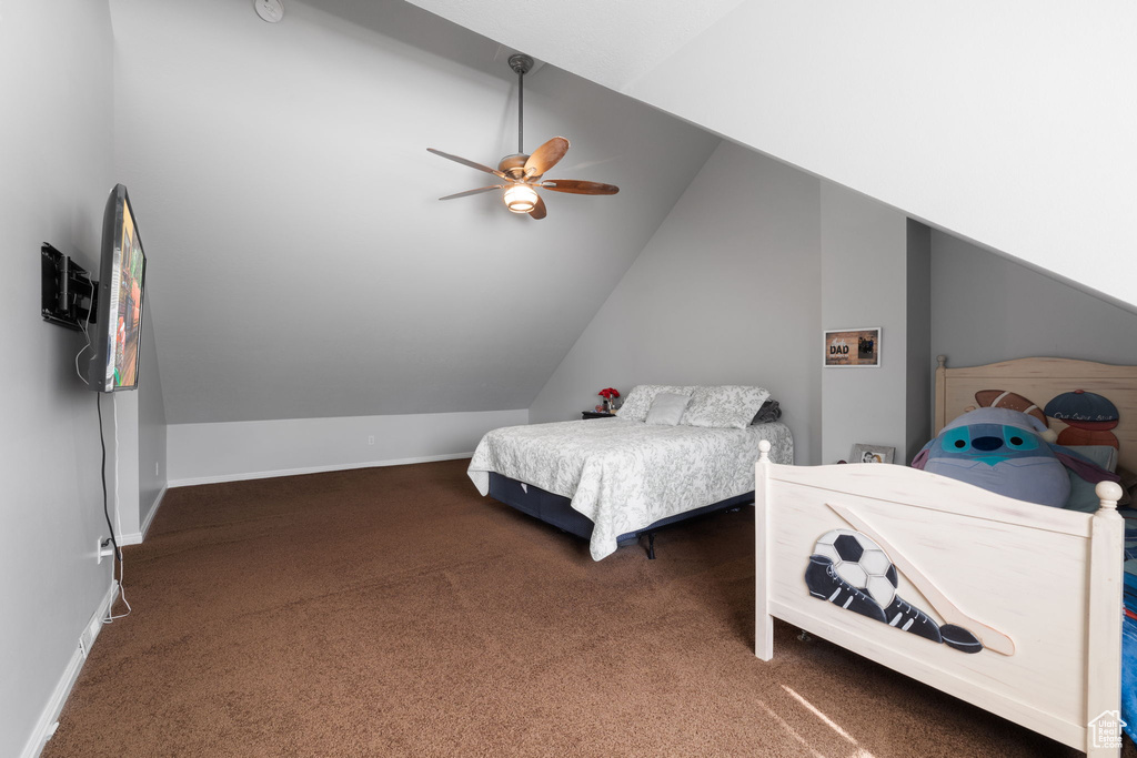 Bedroom with vaulted ceiling, dark colored carpet, and ceiling fan