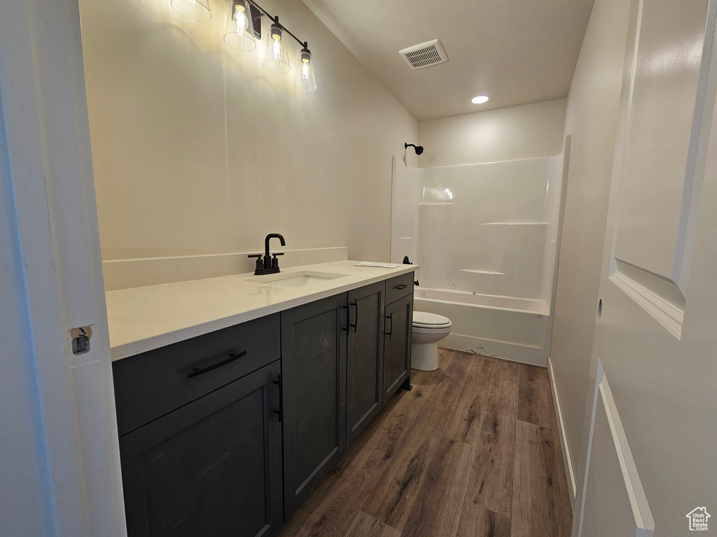 Full bathroom with vanity, wood-type flooring, shower / bathtub combination, and toilet