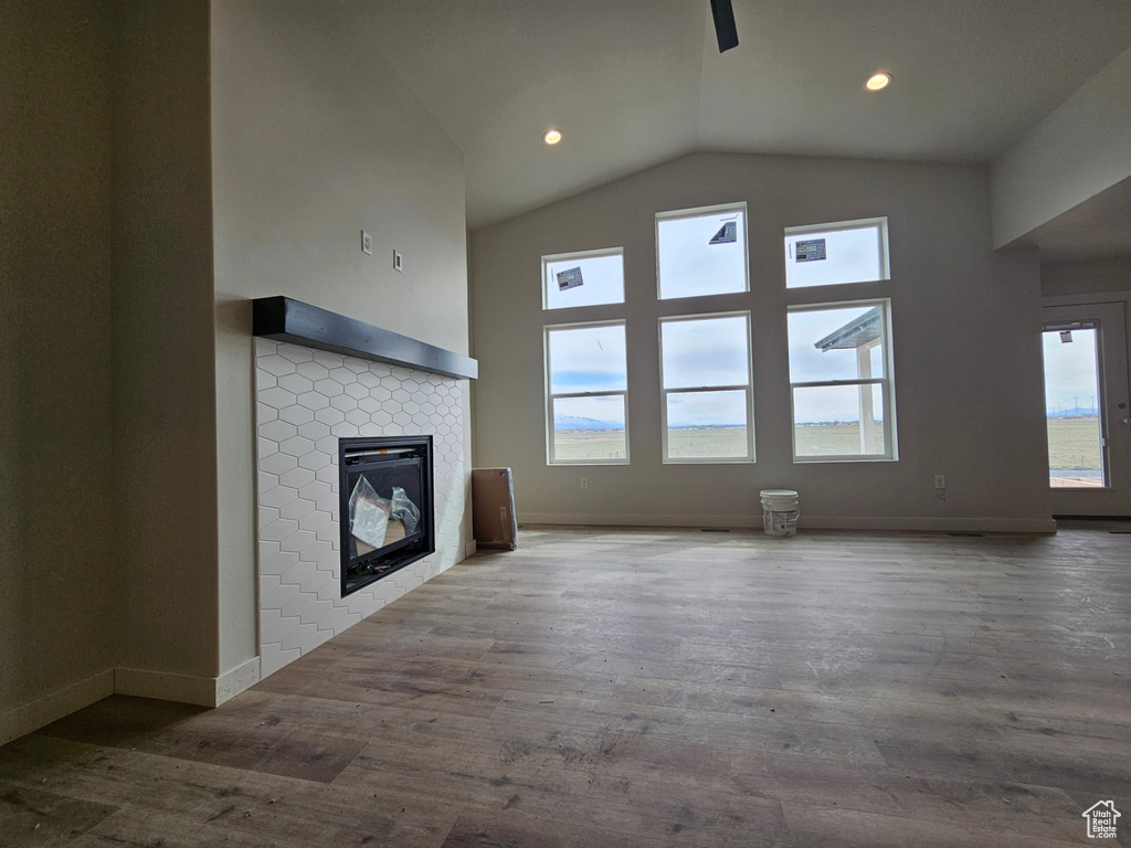Unfurnished living room featuring vaulted ceiling, a tiled fireplace, and dark hardwood / wood-style floors