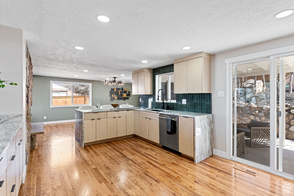 Kitchen featuring stainless steel dishwasher, light hardwood / wood-style floors, and sink