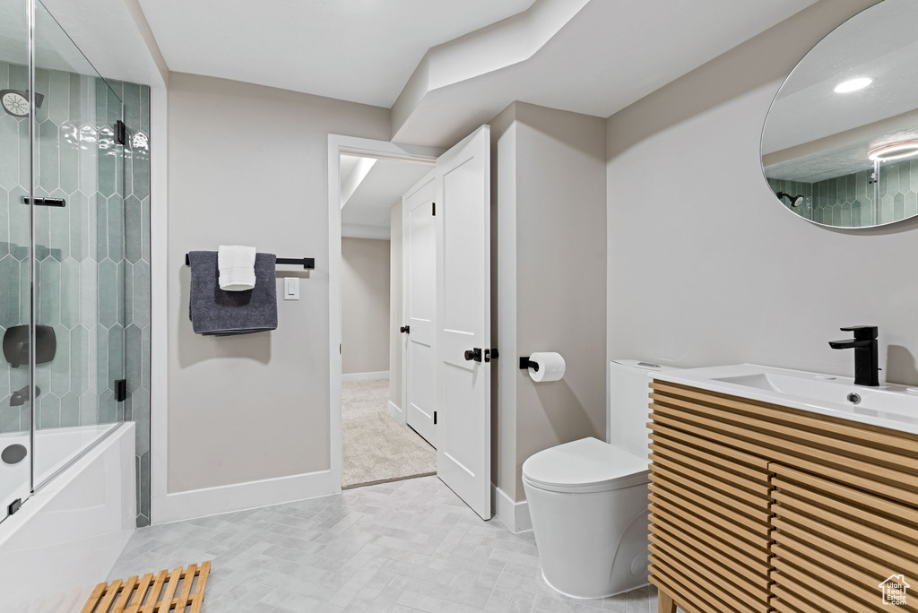 Full bathroom with toilet, tile floors, bath / shower combo with glass door, and vanity