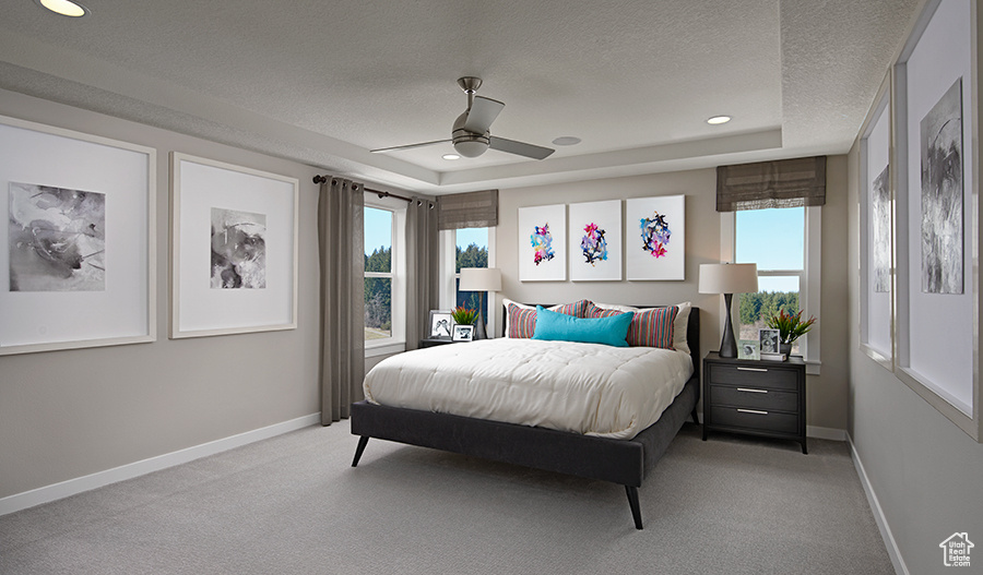 Carpeted bedroom featuring a raised ceiling, a textured ceiling, and ceiling fan
