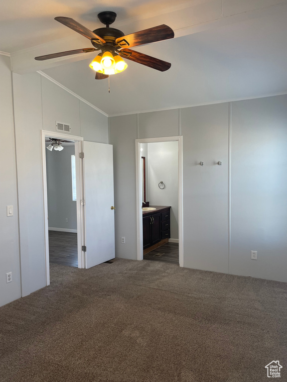 Unfurnished bedroom featuring ensuite bath, dark carpet, lofted ceiling, and ceiling fan