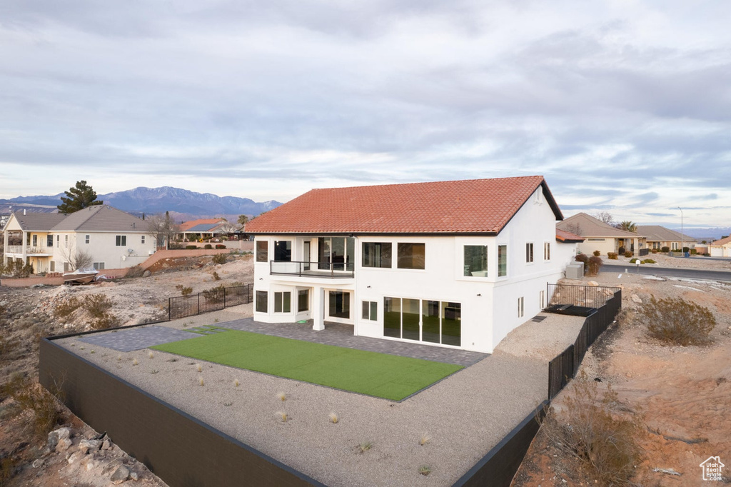 Rear view of house with a patio area, a balcony, and a mountain view