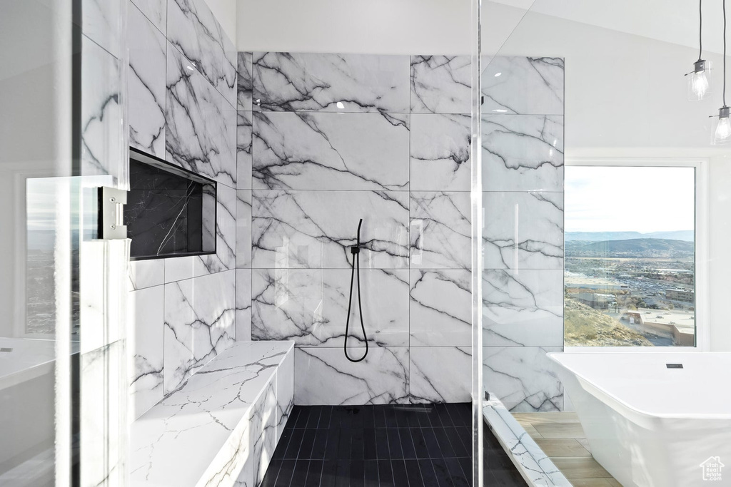 Bathroom featuring lofted ceiling, tile walls, a bath, tile flooring, and a mountain view