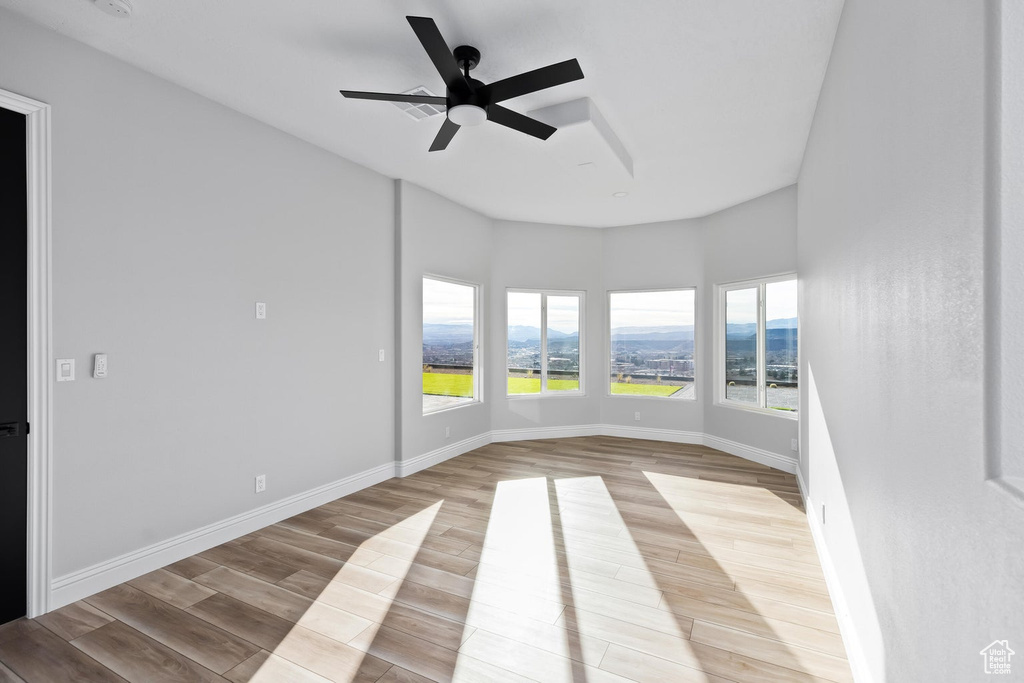 Spare room with a mountain view, light hardwood / wood-style floors, and ceiling fan