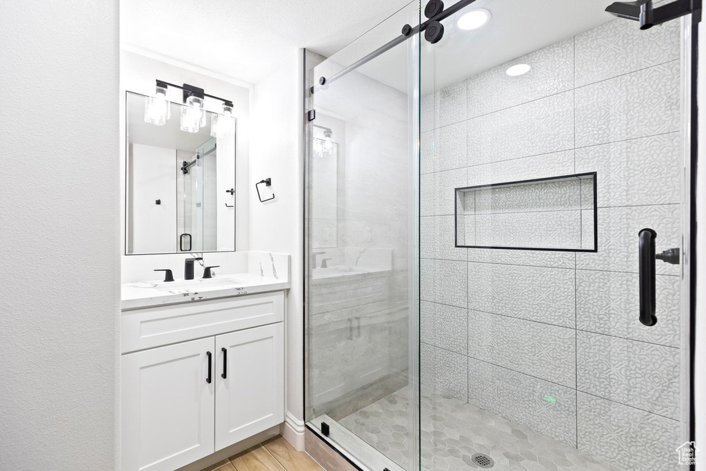 Bathroom with a shower with shower door, oversized vanity, and wood-type flooring
