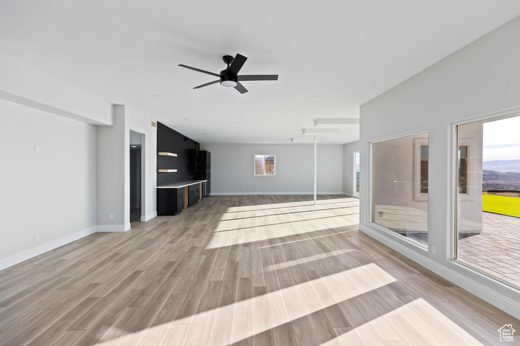 Unfurnished living room with light wood-type flooring and ceiling fan
