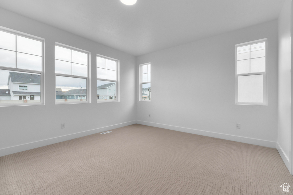 Empty room with a wealth of natural light and light colored carpet