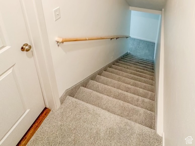 Stairway featuring lofted ceiling, carpet floors, and a textured ceiling