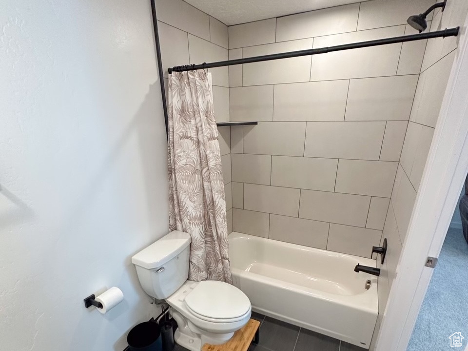 Bathroom with shower / tub combo with curtain, toilet, tile flooring, and a textured ceiling