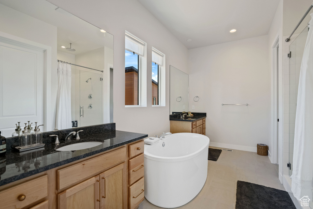 Bathroom with shower with separate bathtub, oversized vanity, tile floors, and dual sinks