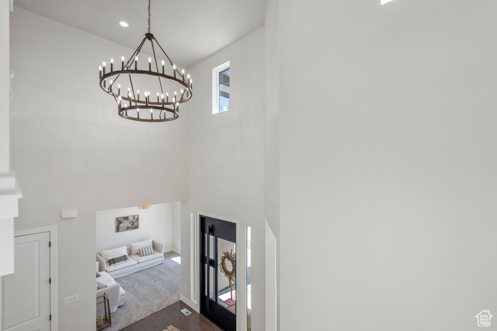 Laundry room with dark carpet, a high ceiling, and a chandelier