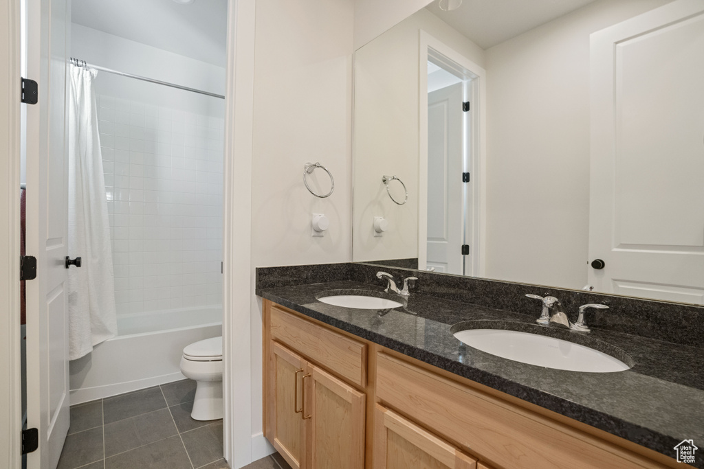 Full bathroom featuring tile flooring, shower / bath combo, double sink vanity, and toilet