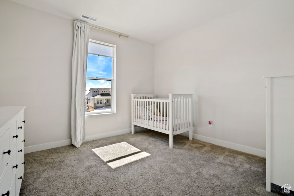 Unfurnished bedroom featuring light colored carpet and a nursery area