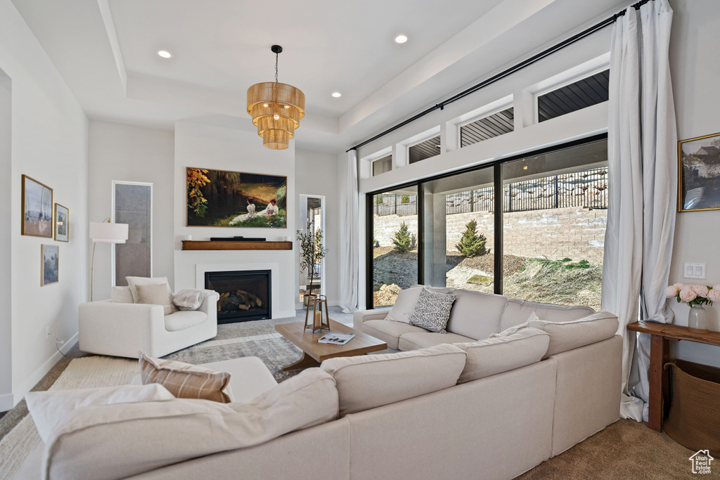 Living room featuring a raised ceiling and an inviting chandelier
