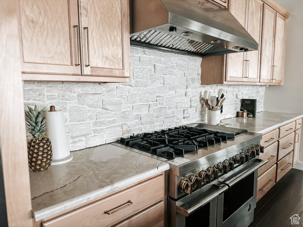 Kitchen featuring dark hardwood / wood-style floors, light brown cabinetry, high end stainless steel range oven, light stone countertops, and wall chimney range hood