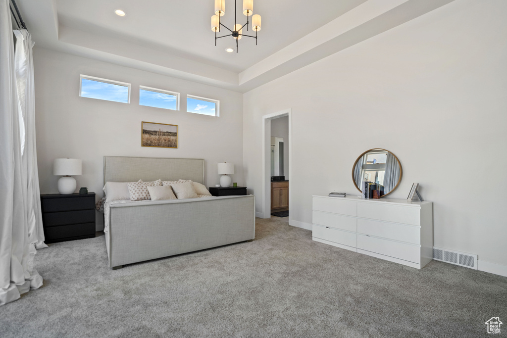 Bedroom featuring a notable chandelier, light carpet, and a tray ceiling