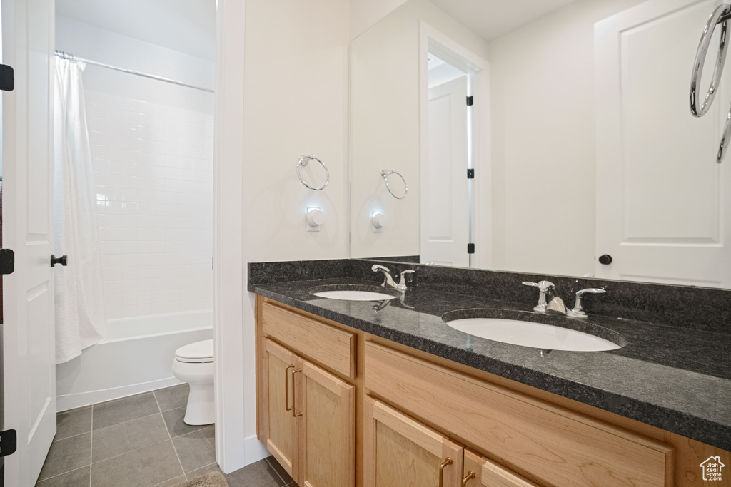 Full bathroom featuring tile floors, oversized vanity, toilet, double sink, and shower / tub combo