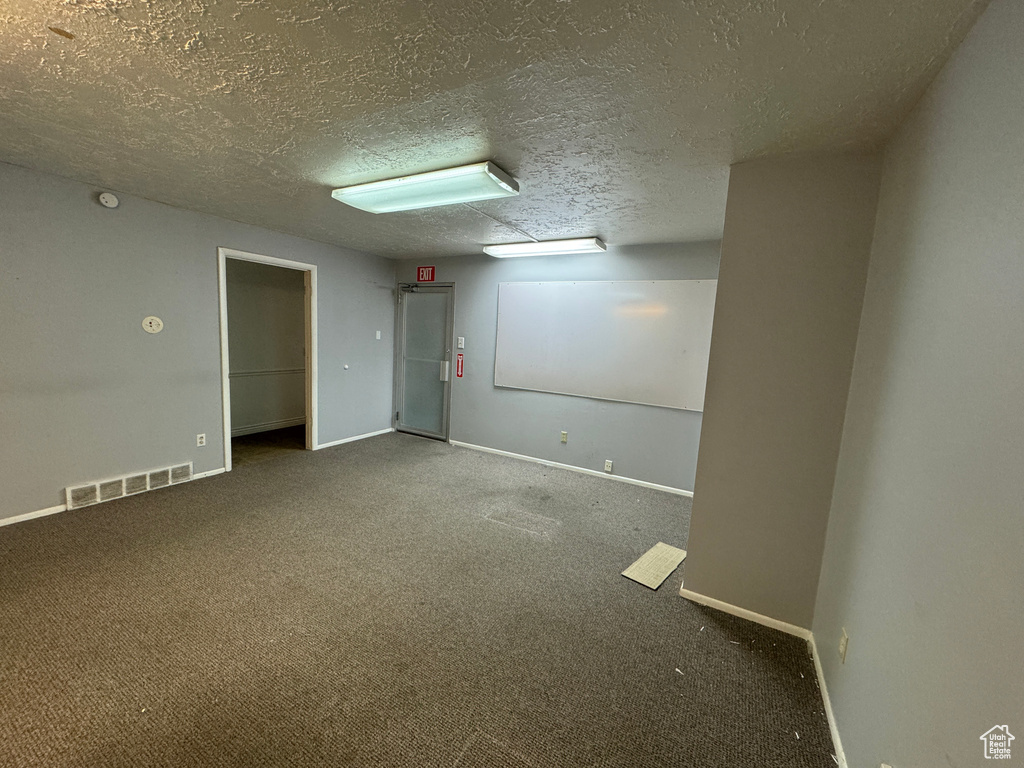 Unfurnished room with dark colored carpet and a textured ceiling