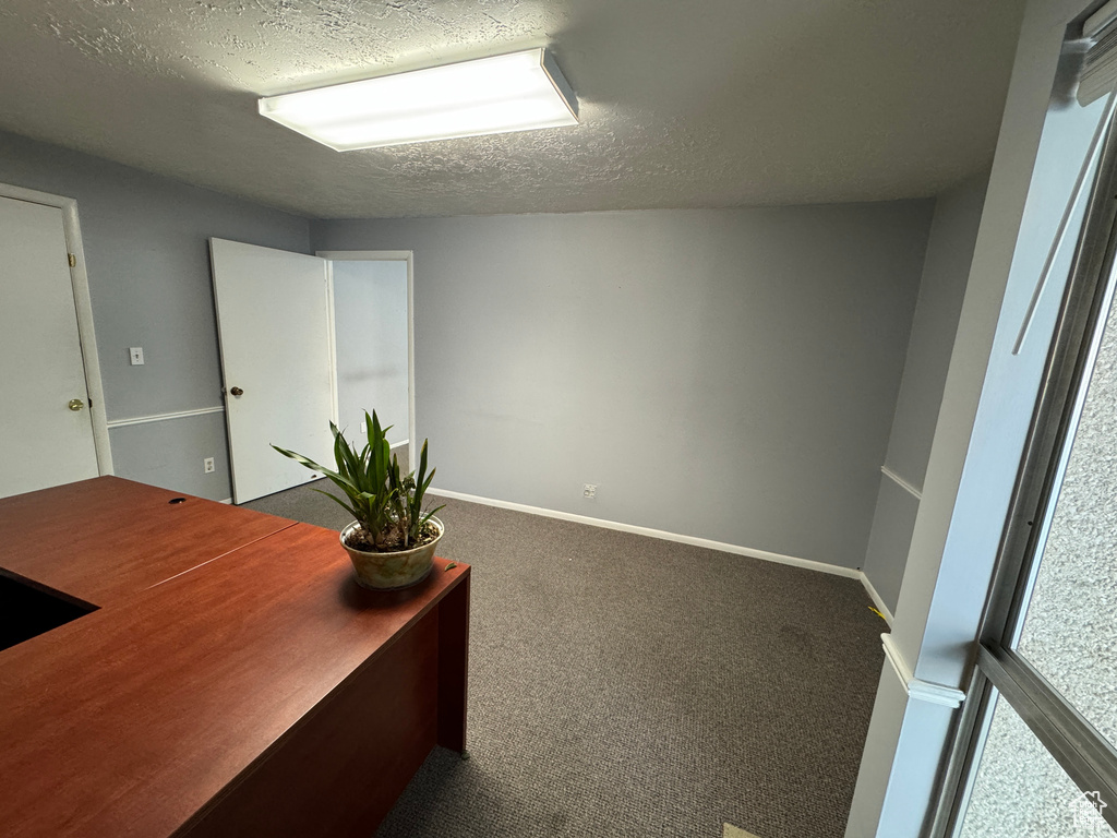 Office area featuring dark carpet and a textured ceiling