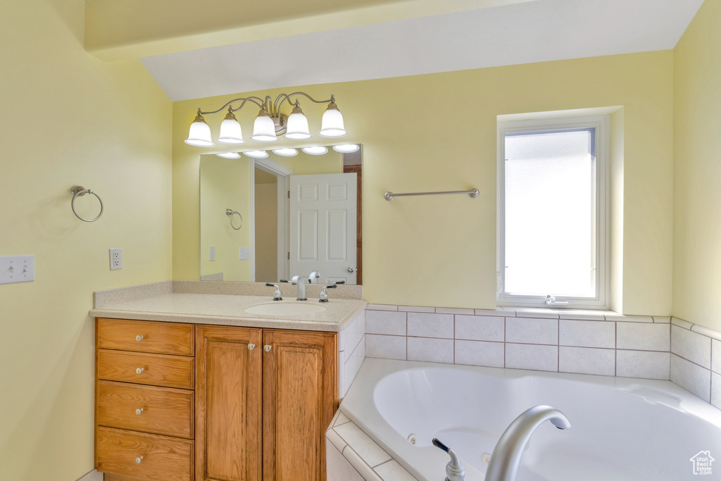 Bathroom featuring vaulted ceiling with beams, vanity, and a relaxing tiled bath