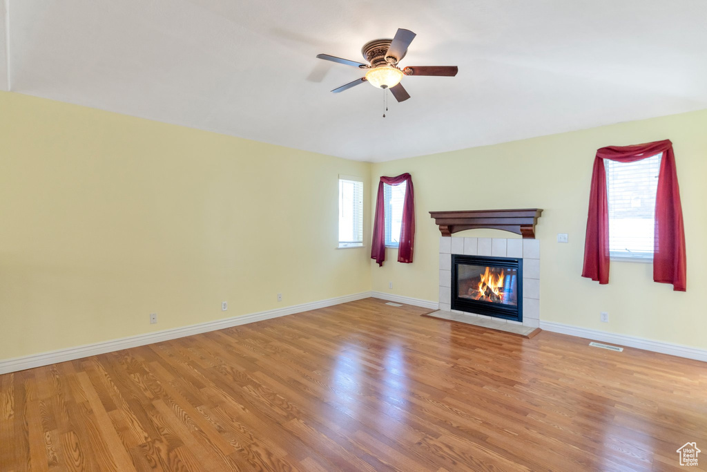 Unfurnished living room with a tile fireplace, light hardwood / wood-style flooring, and ceiling fan