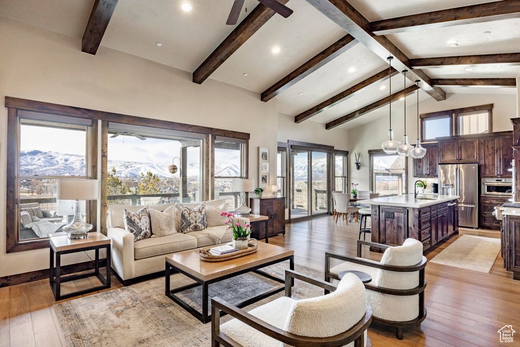 Living room featuring a mountain view, high vaulted ceiling, ceiling fan with notable chandelier, and light hardwood / wood-style floors