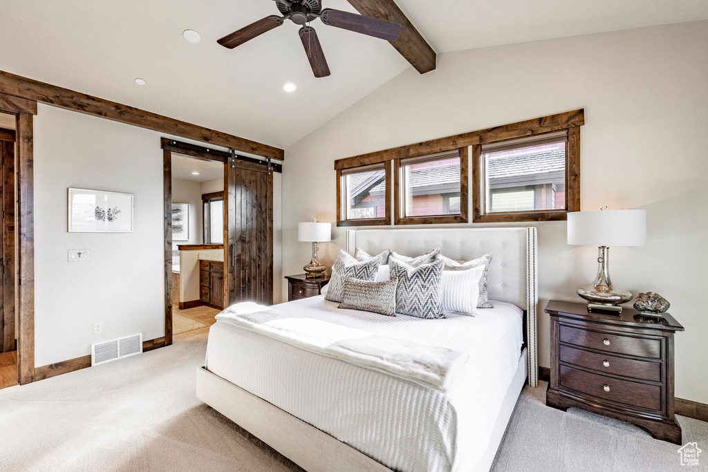 Bedroom featuring a barn door, light colored carpet, connected bathroom, and lofted ceiling with beams