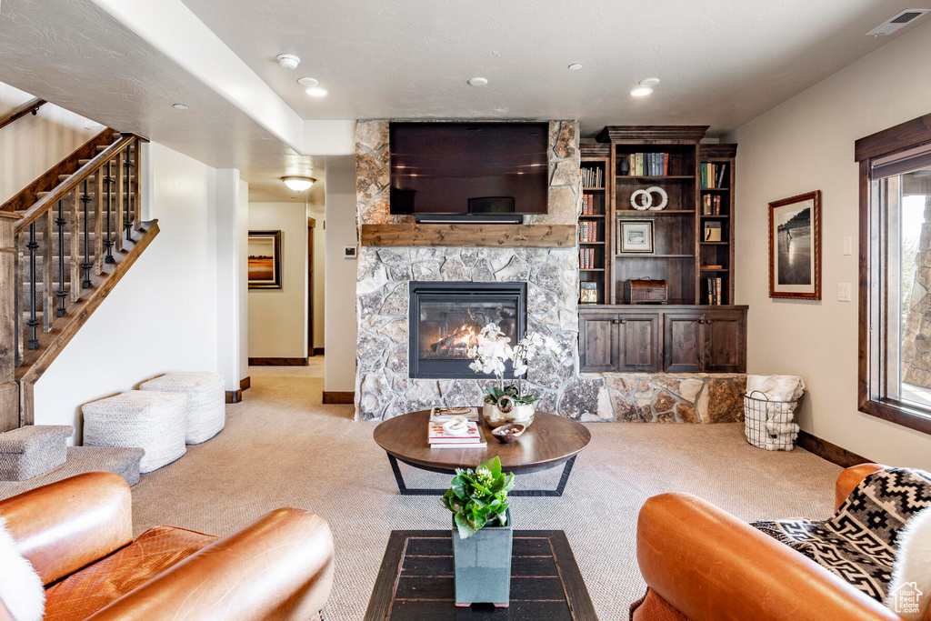 Living room with a stone fireplace and light colored carpet