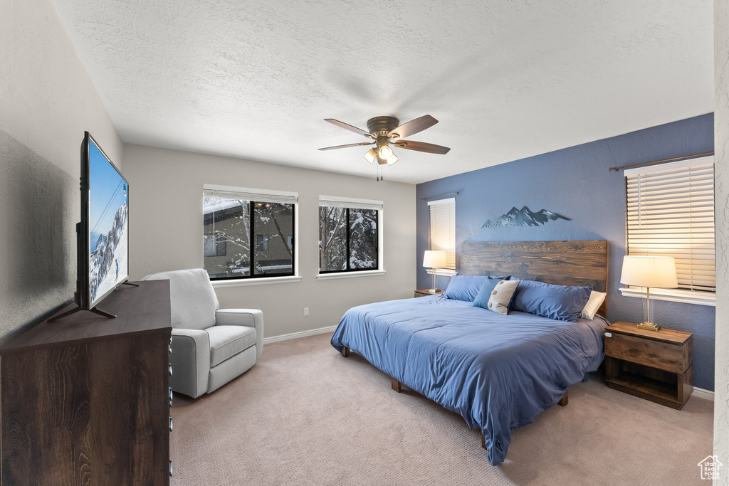 Bedroom with a textured ceiling, light carpet, and ceiling fan