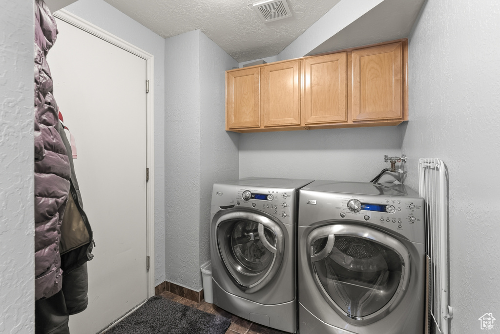 Laundry room featuring cabinets, a textured ceiling, washer hookup, washer and clothes dryer, and dark wood-type flooring