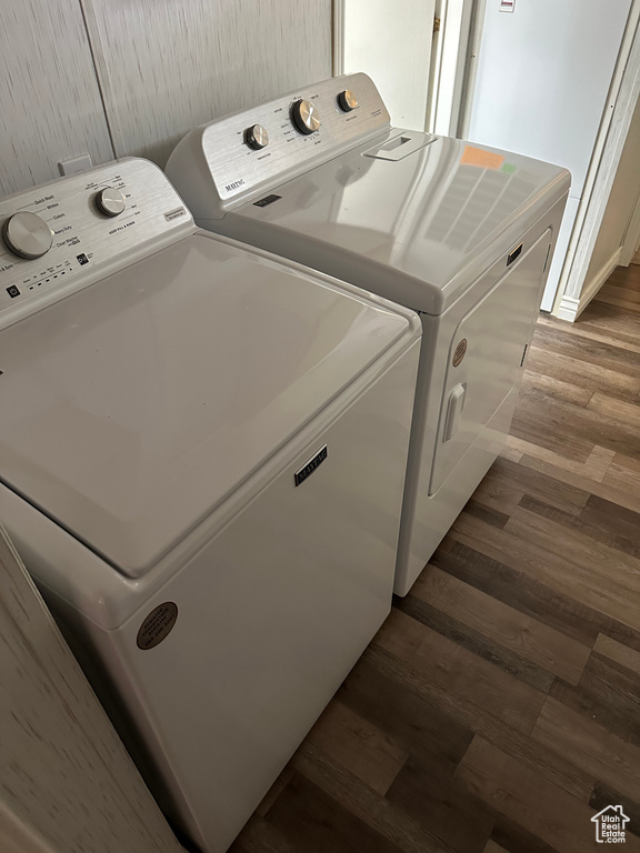 Washroom with dark wood-type flooring and washing machine and clothes dryer