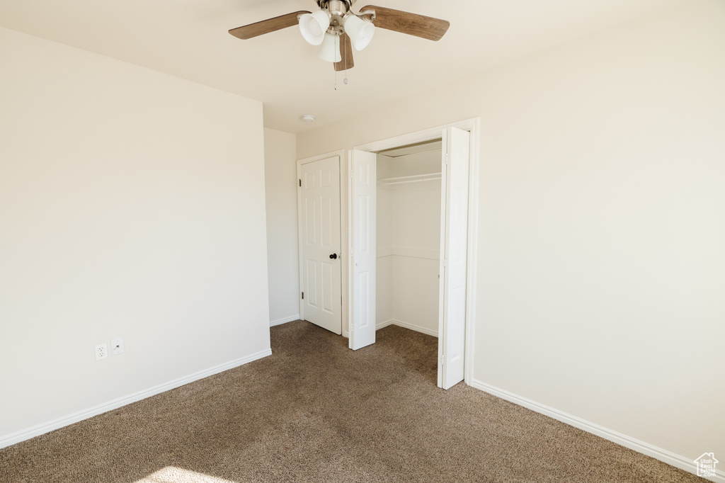 Unfurnished bedroom with a closet, dark colored carpet, and ceiling fan