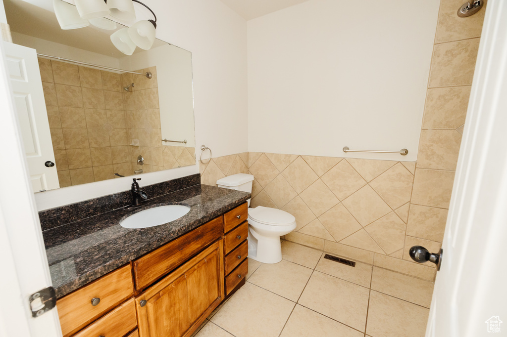 Bathroom with tile floors, toilet, tile walls, and oversized vanity