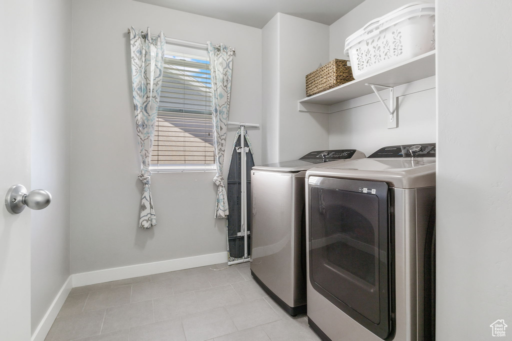 Washroom with light tile flooring and washer and clothes dryer