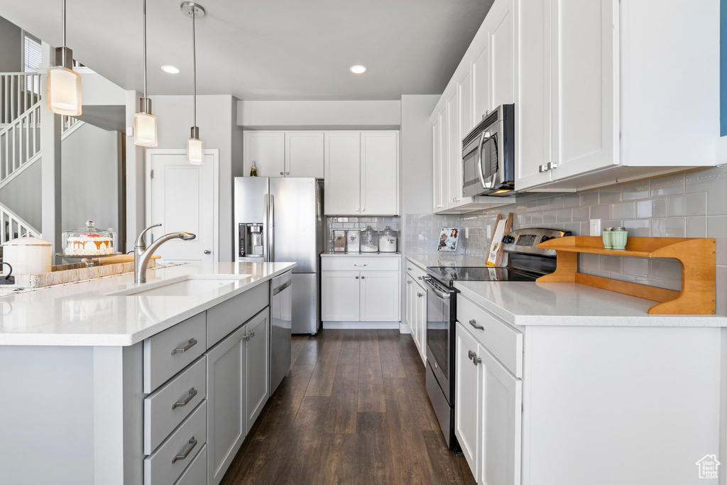 Kitchen with sink, hanging light fixtures, dark hardwood / wood-style flooring, backsplash, and stainless steel appliances