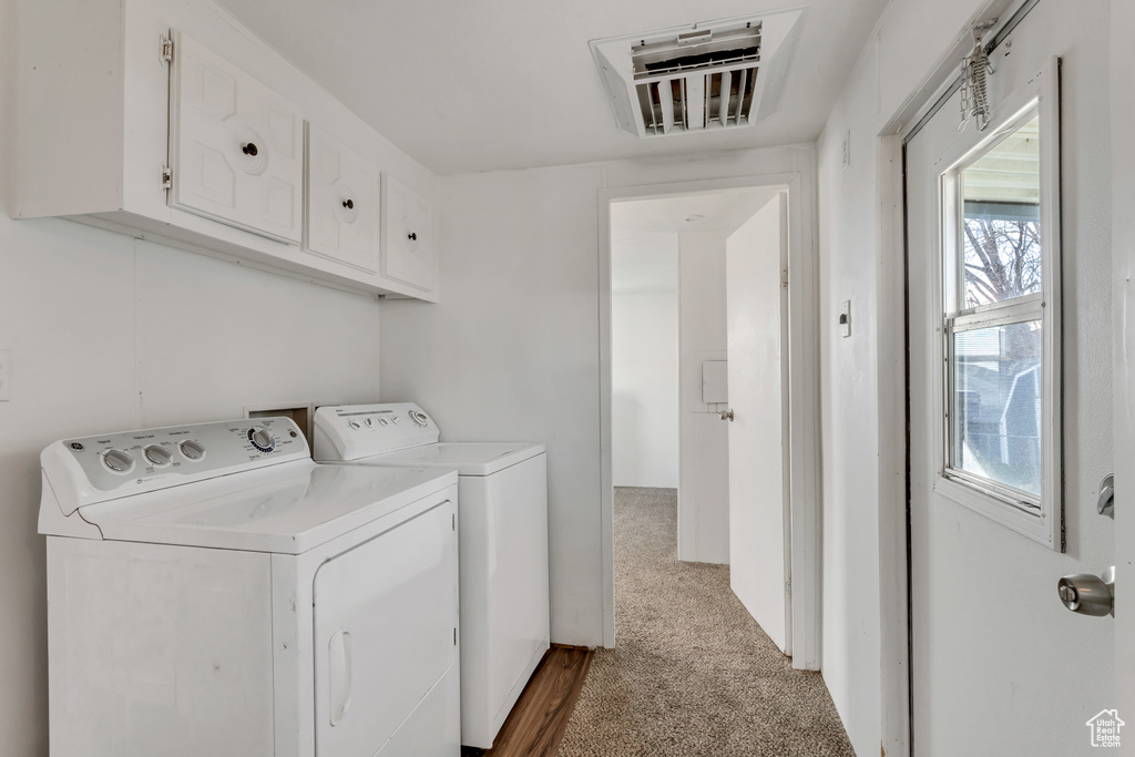 Laundry room with independent washer and dryer, cabinets, light carpet, and a wealth of natural light