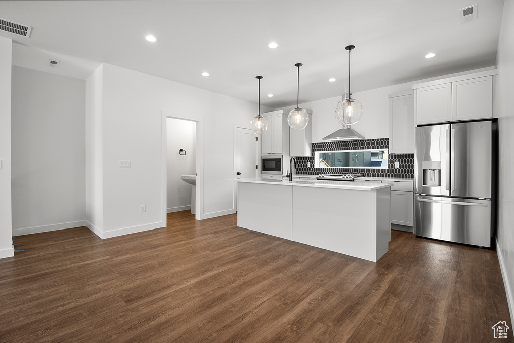 Kitchen with dark wood-type flooring, white cabinets, an island with sink, and stainless steel appliances