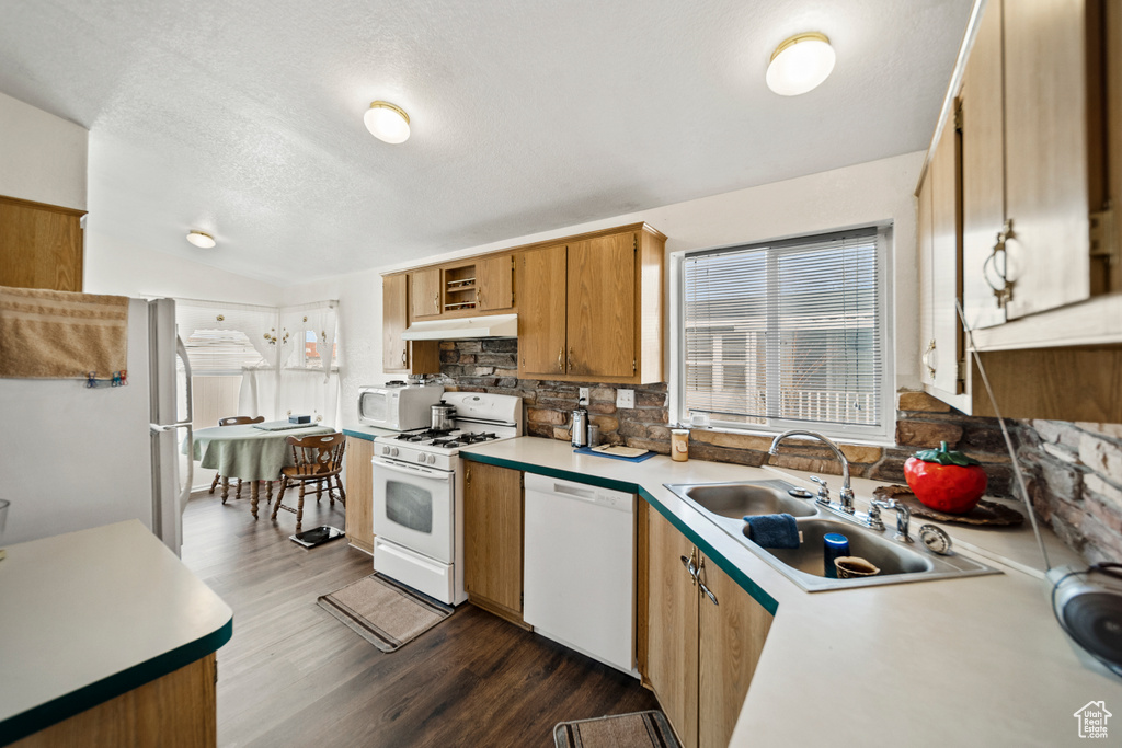 Kitchen with sink, white appliances, dark hardwood / wood-style floors, and backsplash