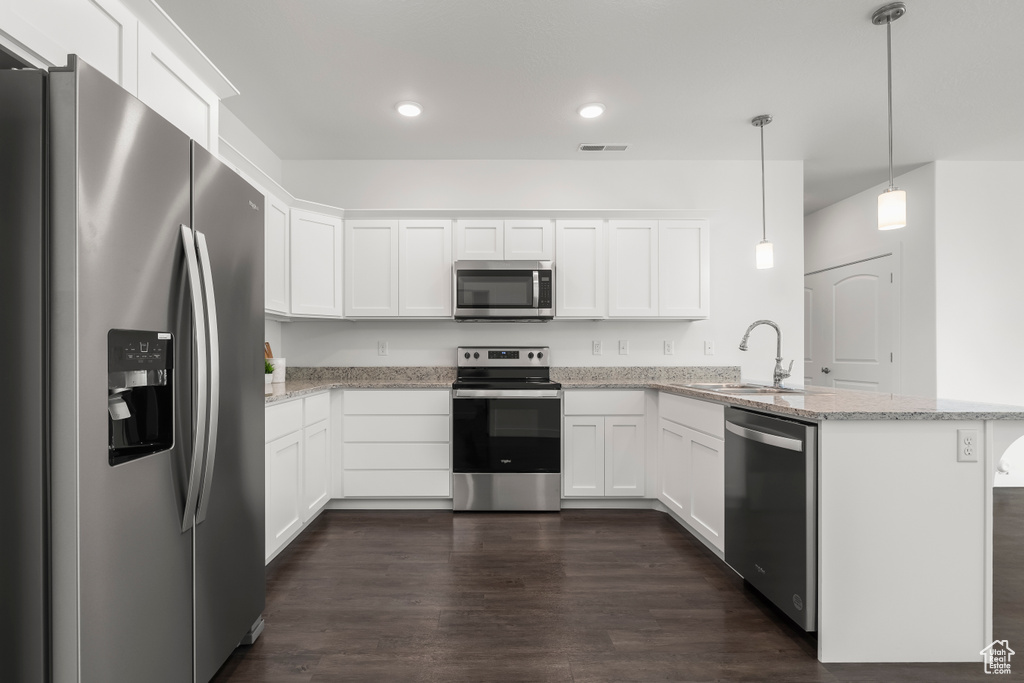 Kitchen with decorative light fixtures, white cabinetry, stainless steel appliances, and dark wood-type flooring