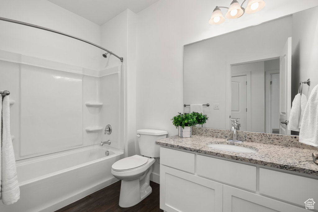 Full bathroom with shower / bathtub combination, hardwood / wood-style floors, large vanity, and toilet
